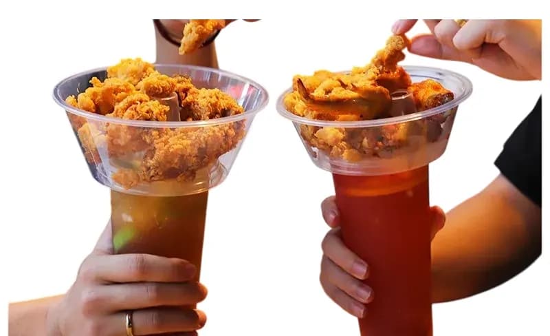 Two hands holding Cupify sets, fried chicken in the bowls and iced drinks below